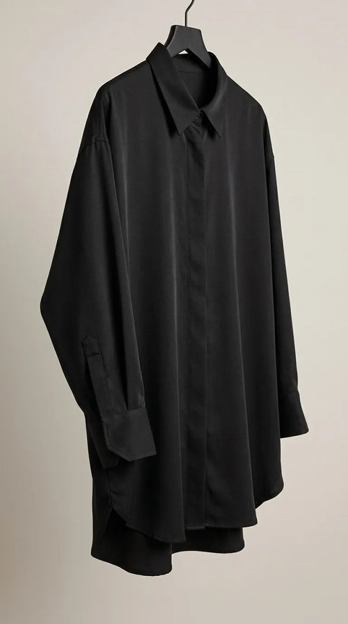 Black oversized shirt with pointed collar and button cuffs hanging on a hanger