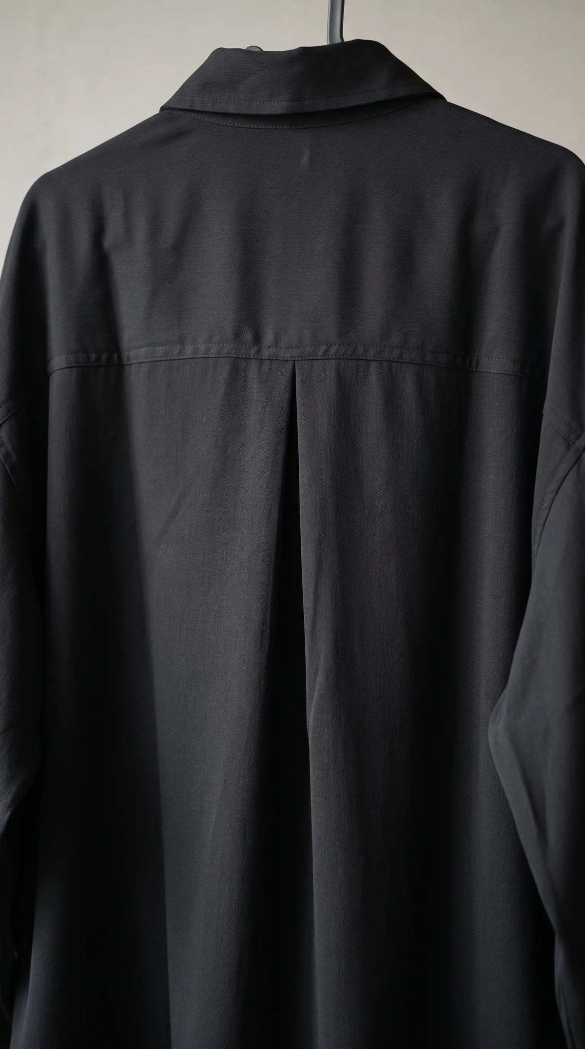 Close-up of the black shirt's back yoke seam and center box pleat