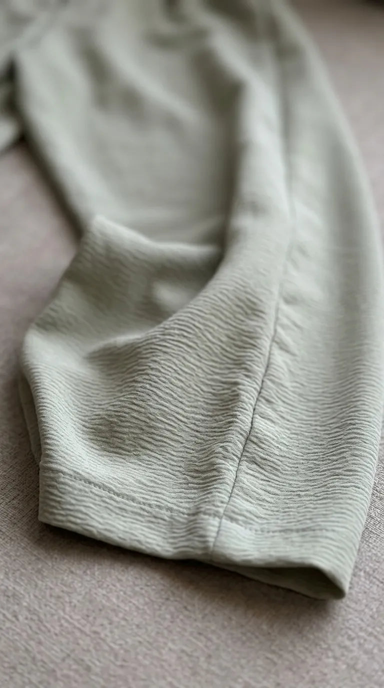 Close-up of the matcha sage-green crinkle-crepe fabric and hem