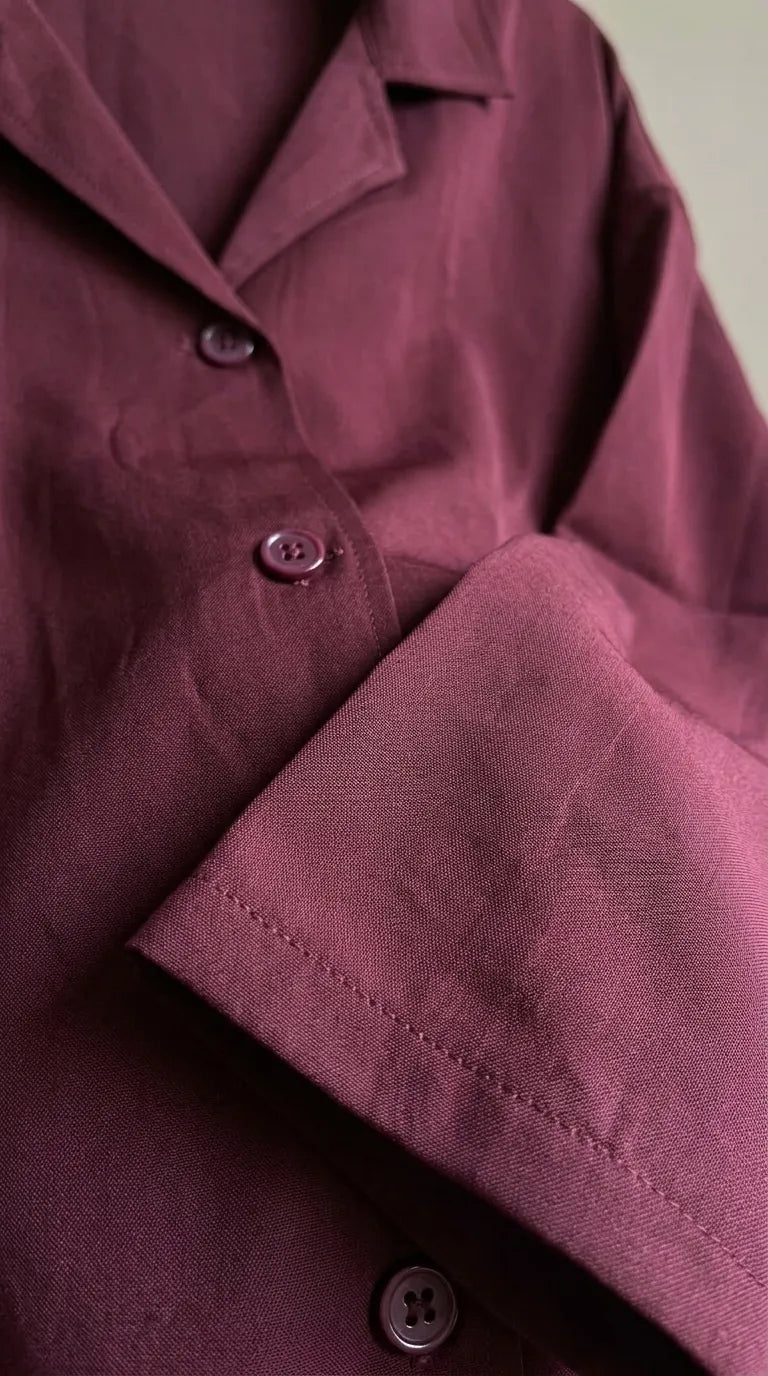 Close-up of the maroon shirt's notch collar, buttons and sleeve hem