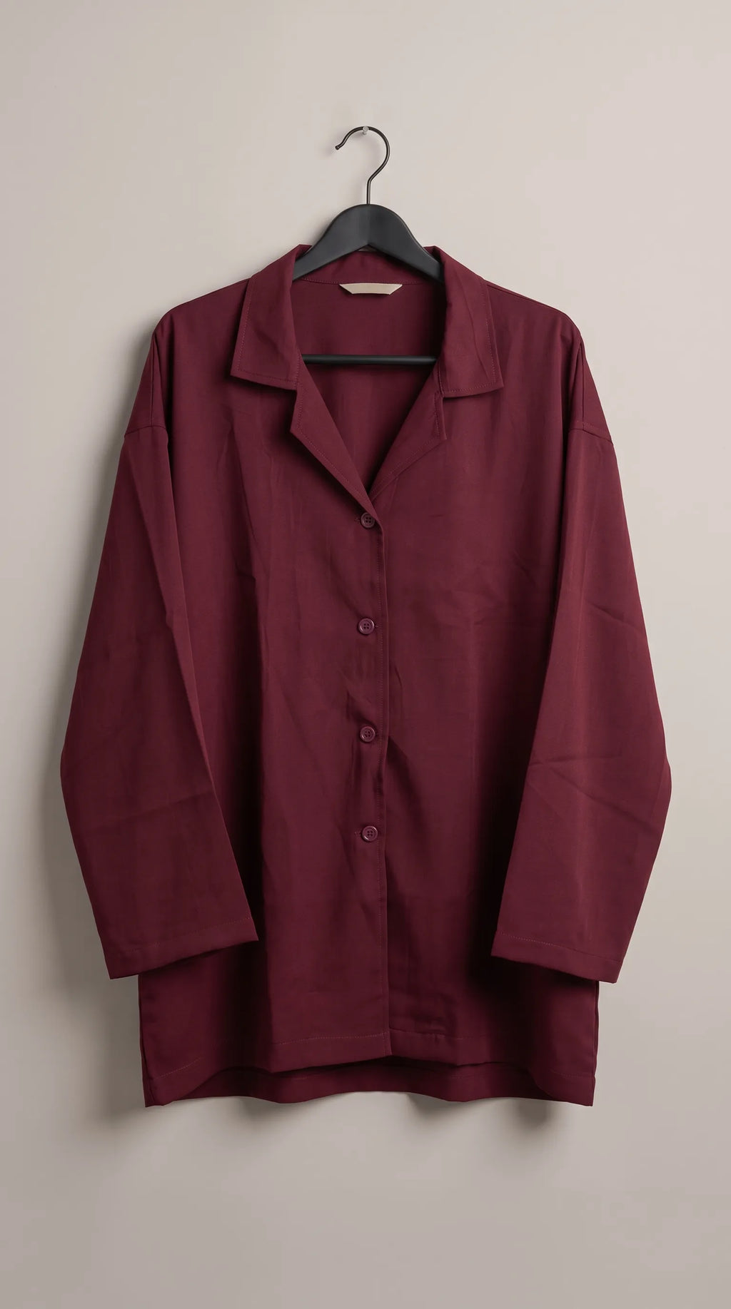 Maroon oversized camp-collar button-down shirt hanging on a hanger, front view