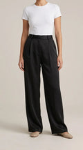 Black high-rise pleated wide-leg trousers worn by a model, front view