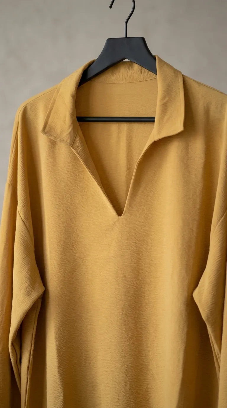 Close-up of the mustard tunic's deep V-neckline and spread collar on a hanger