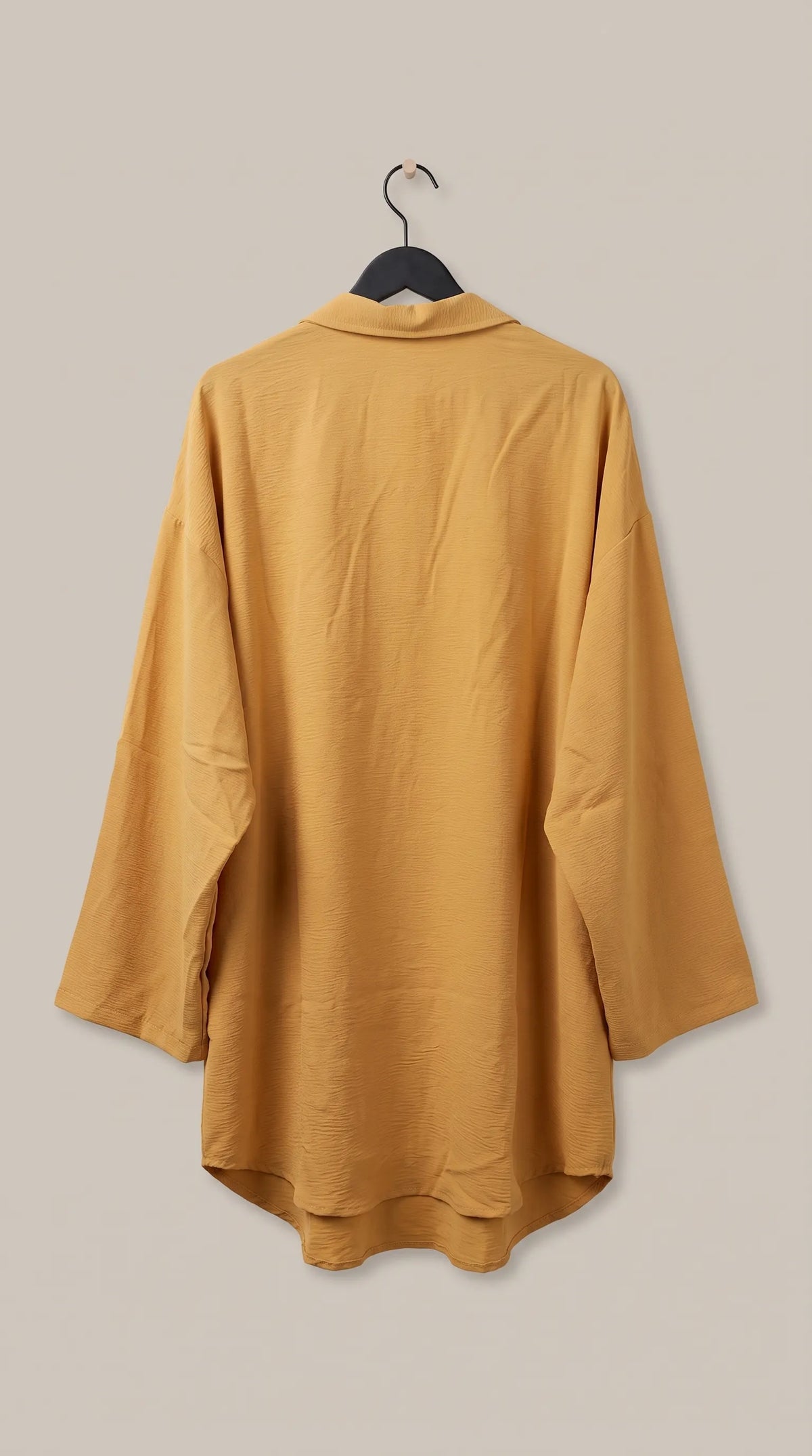 Back view of the mustard oversized tunic on a hanger