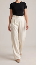 Ivory off-white wide-leg trousers worn by a model walking toward the camera, front view
