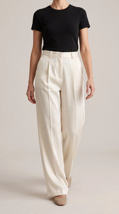 Ivory off-white wide-leg trousers worn by a model walking toward the camera, front view