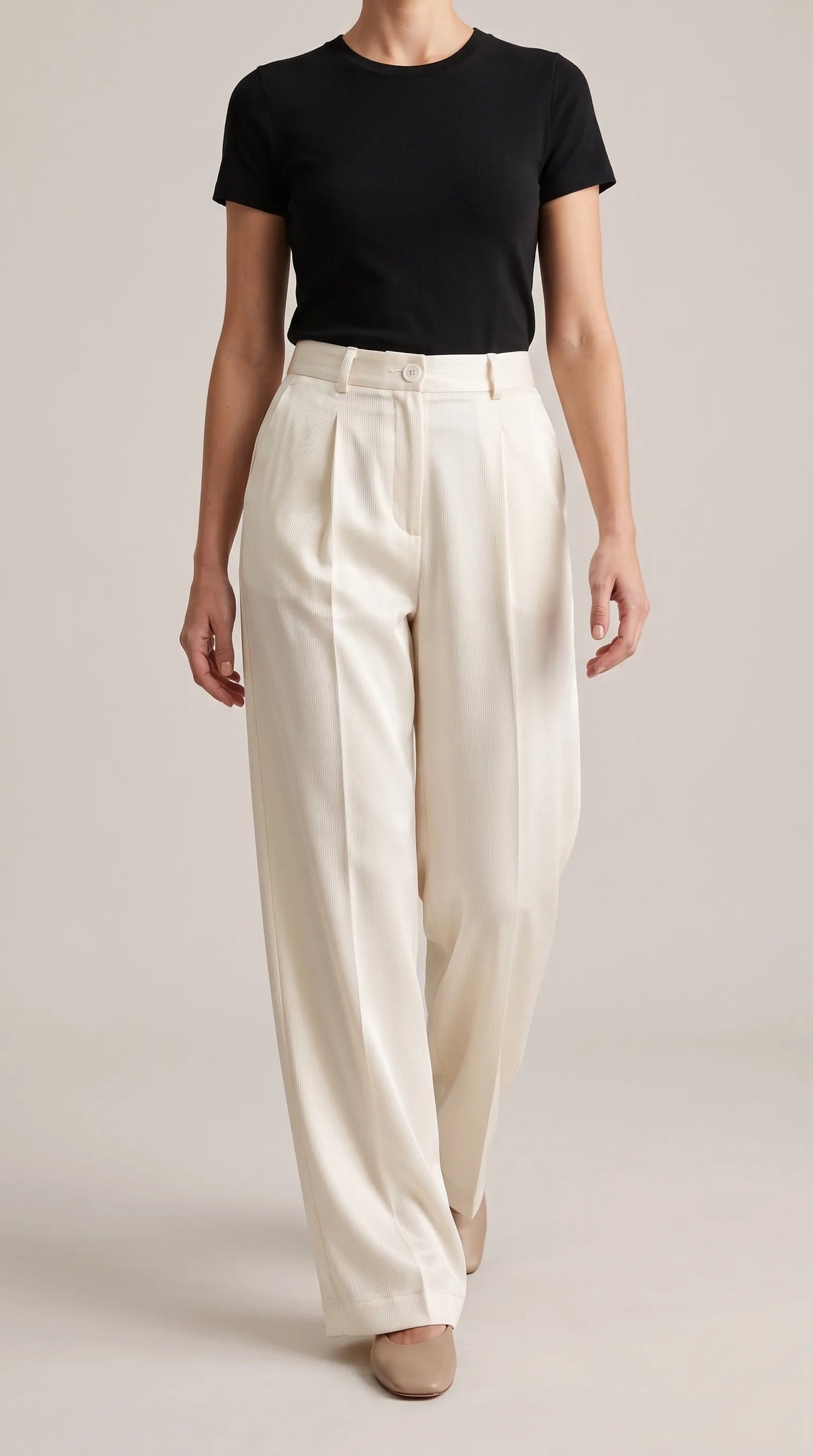 Ivory off-white wide-leg trousers worn by a model walking toward the camera, front view